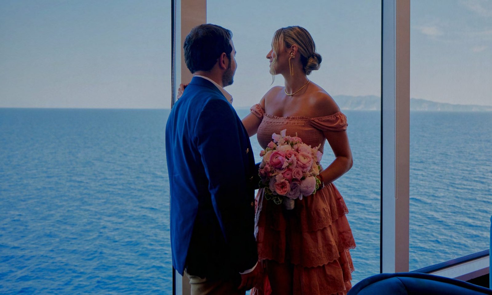 A couple in wedding attire looking out at the sea from a Virgin Voyages ship