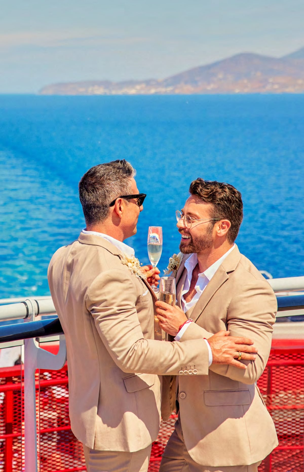 Two grooms toasting with champagne on deck