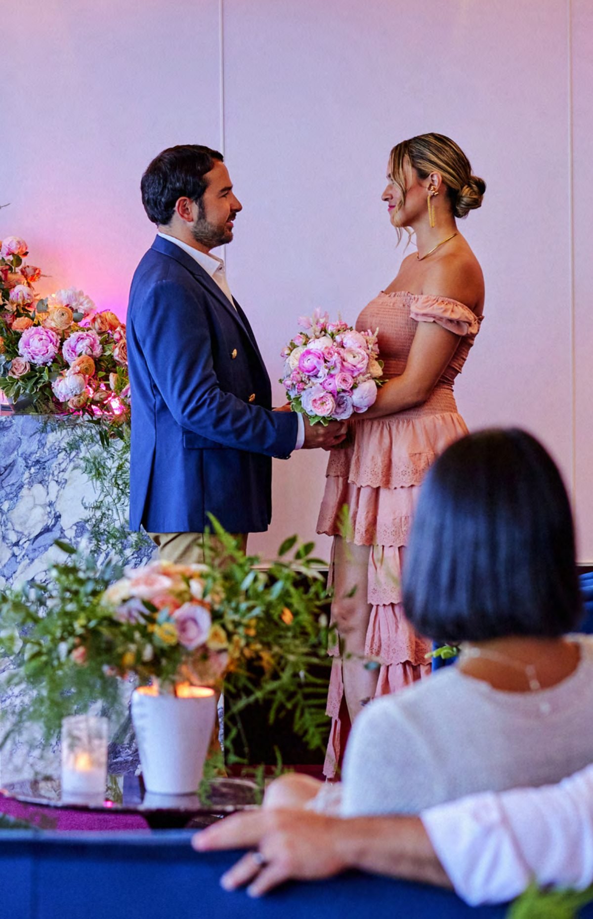 A couple exchanging vows in an intimate flower-filled venue