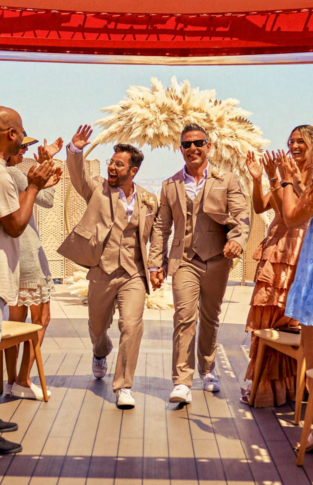 A newly married couple walking down the aisle on the ship's top deck as guests cheer